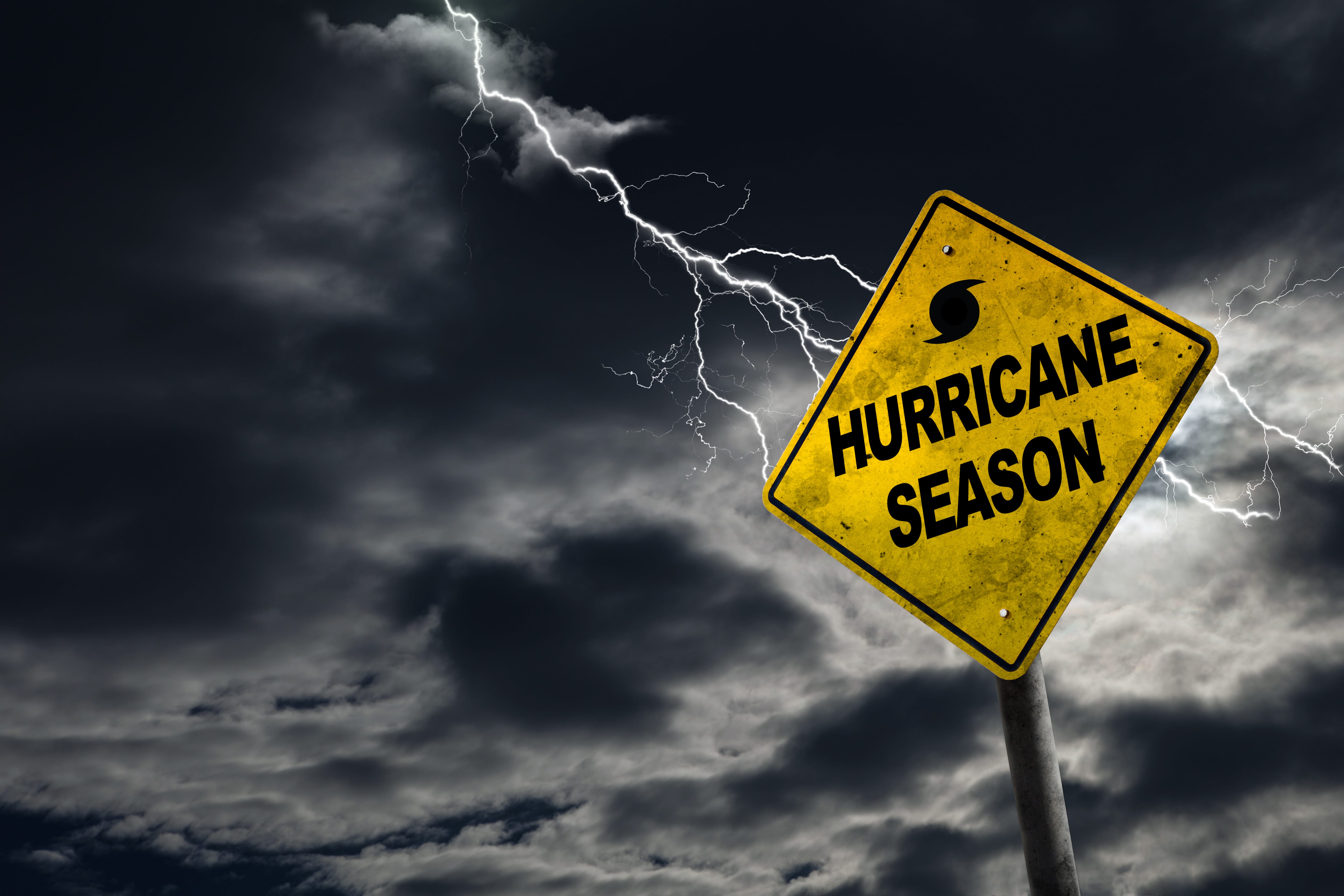 A dark sky with lightning strikes and a caution sign reading 'Hurricane Season,' emphasizing the dangers of storms like Hurricane Milton with potential landfall in Florida.