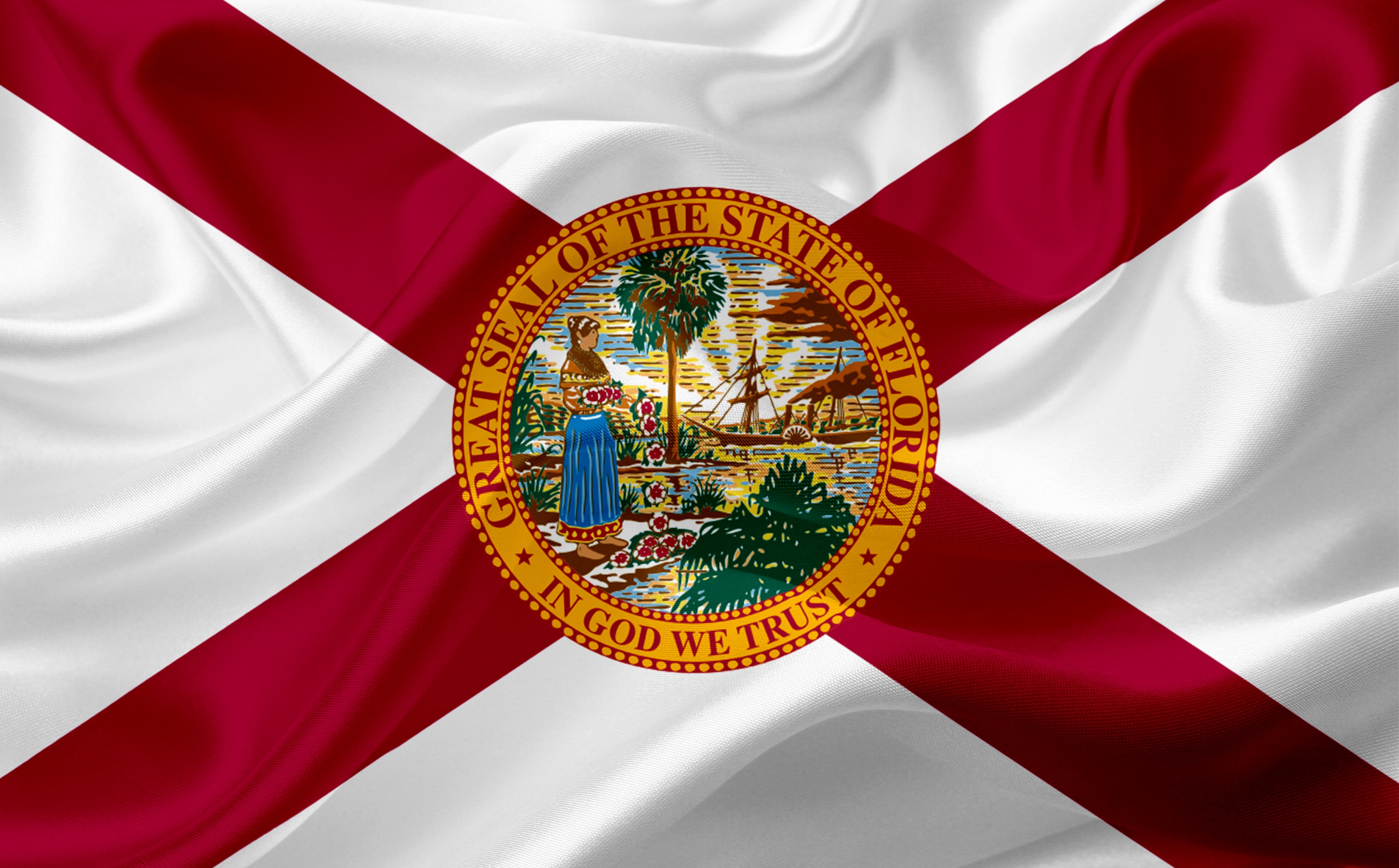 The flag of Florida waving in the wind, featuring the state seal, representing Florida laws, real estate regulations, and local property management policies.