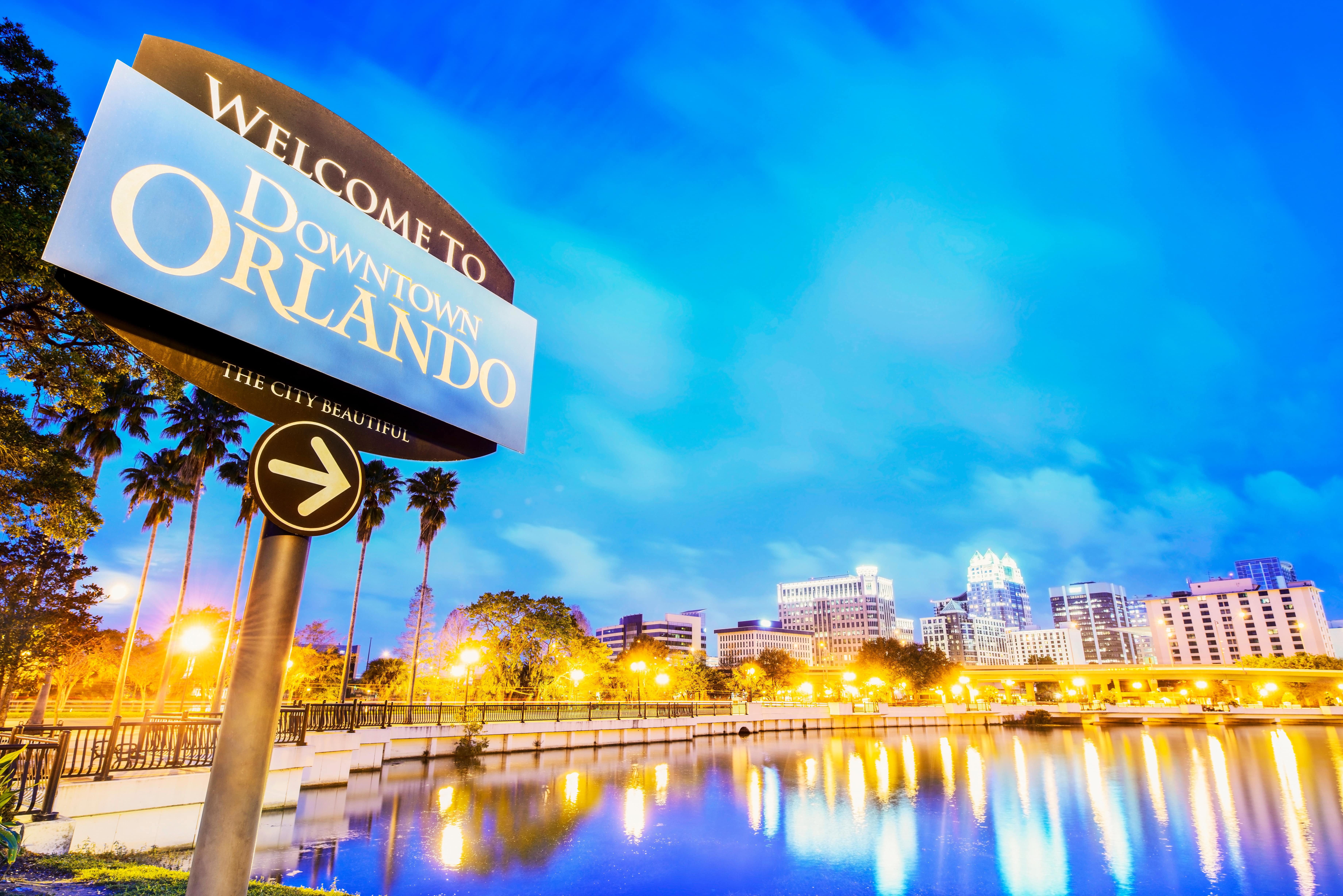 Welcome to Downtown Orlando sign with a cityscape in the background at dusk, representing Florida real estate and urban living.