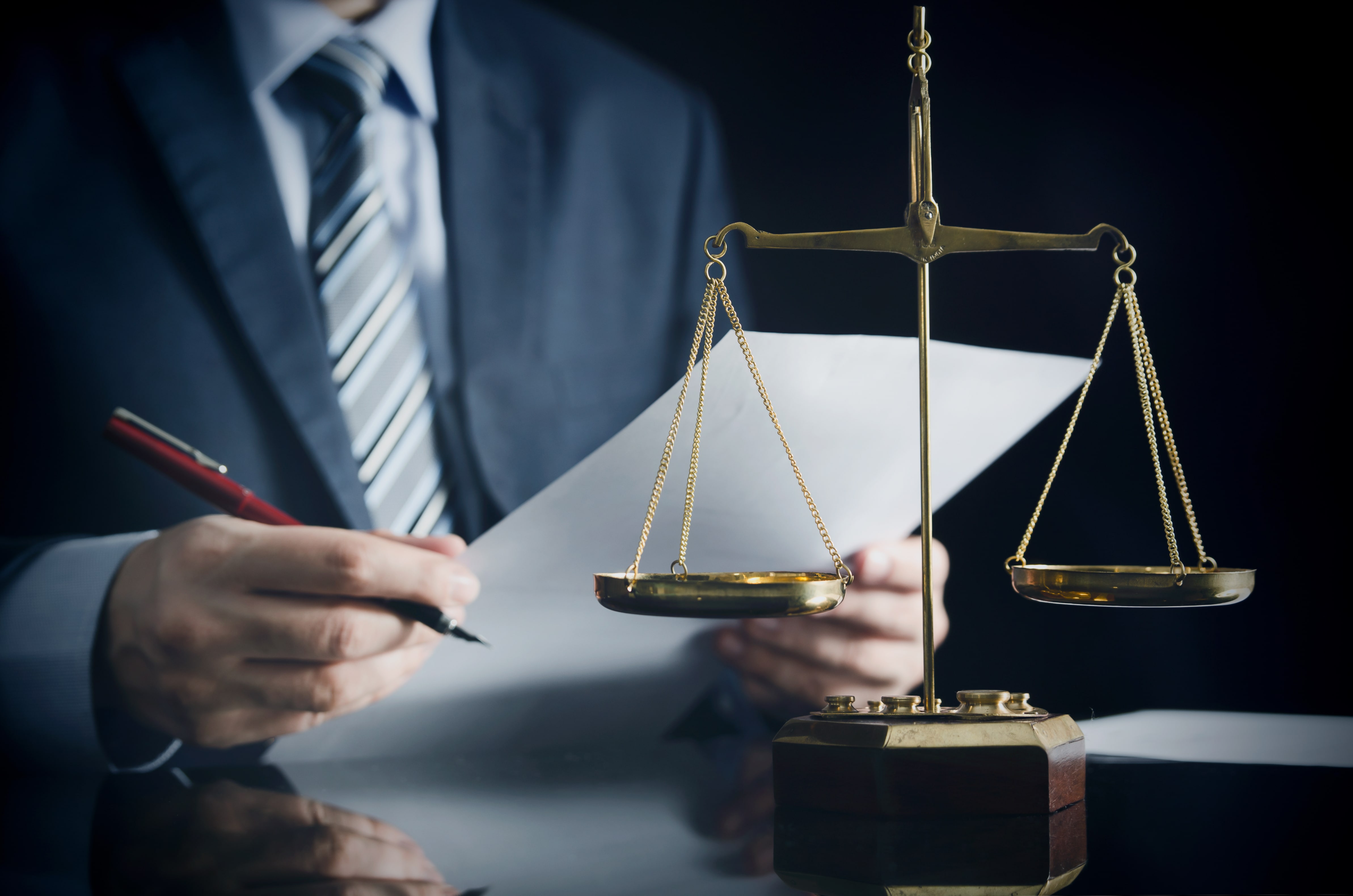 Scales of justice in the foreground with a businessman reviewing documents, symbolizing legal compliance in fair housing.