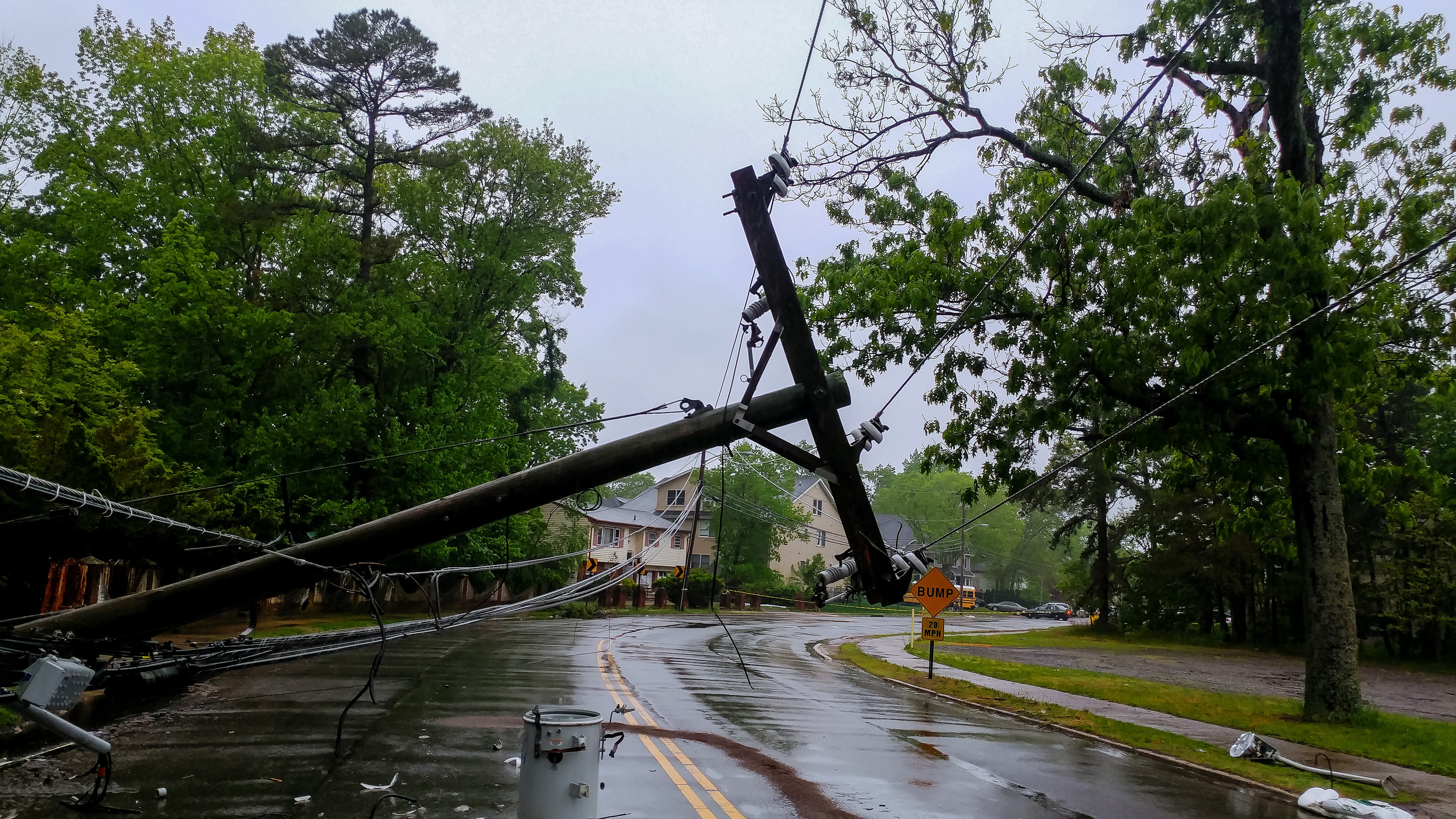 A downed power pole leans over a wet road after a storm, depicting the aftermath of a hurricane like Milton.