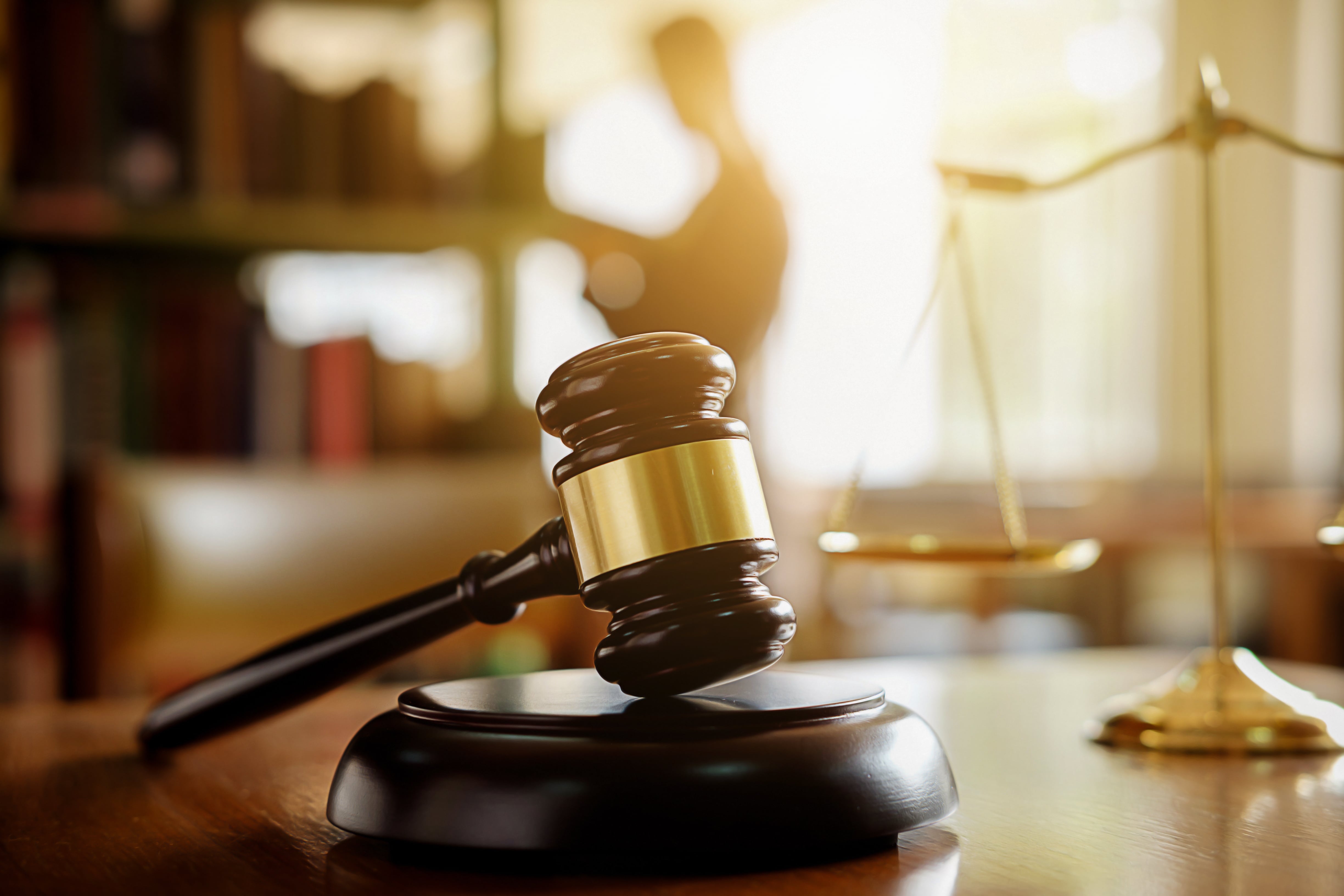 A wooden judge’s gavel resting on a desk with golden legal scales in the background, symbolizing property law and landlord rights.