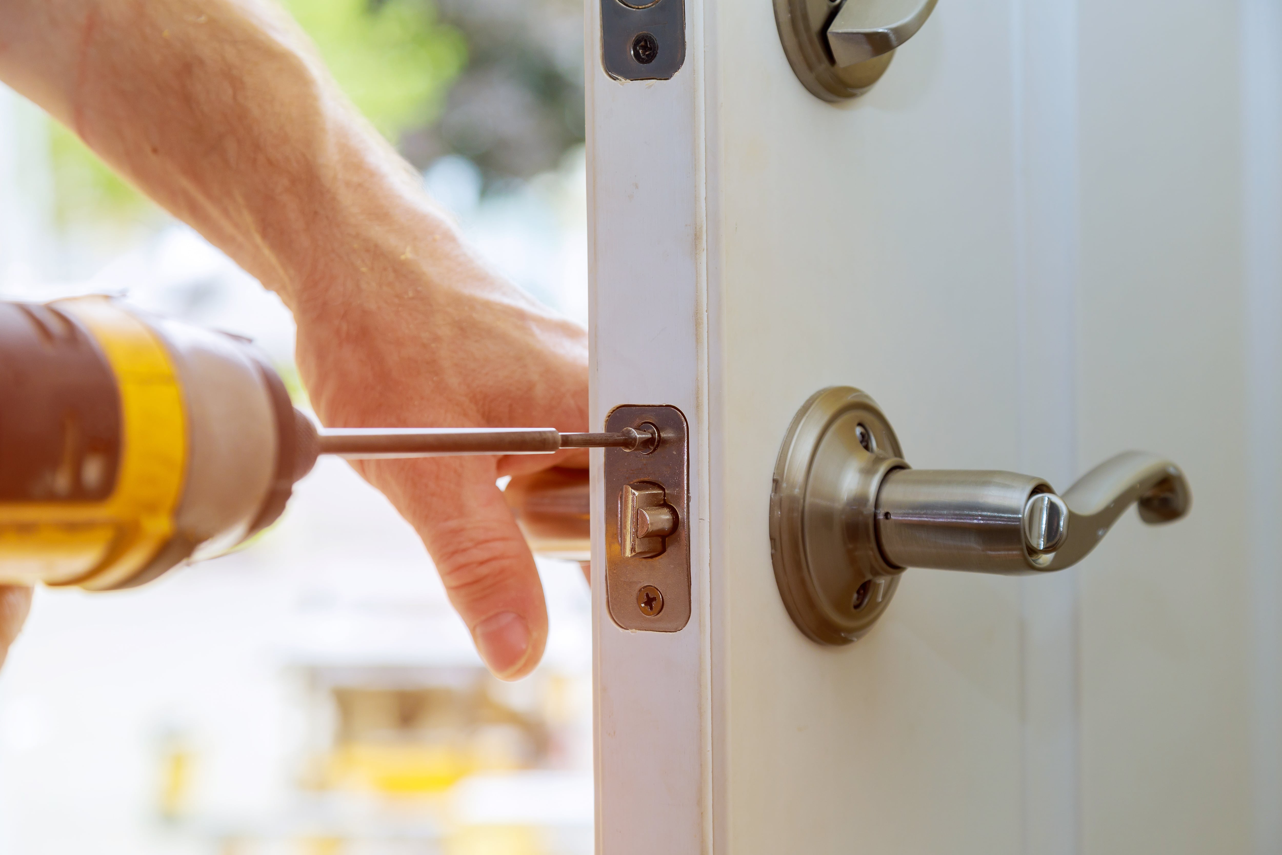 lose-up of a person using a drill to change a door lock, illustrating eviction or securing property.