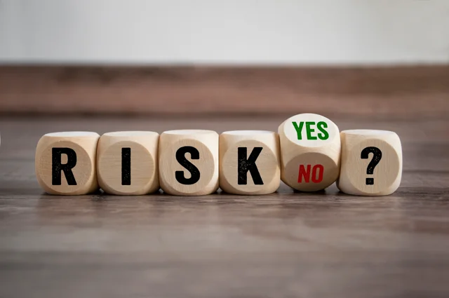 Risk assessment concept showing wooden cubes spelling RISK with yes and no options, symbolizing decision-making in property management.