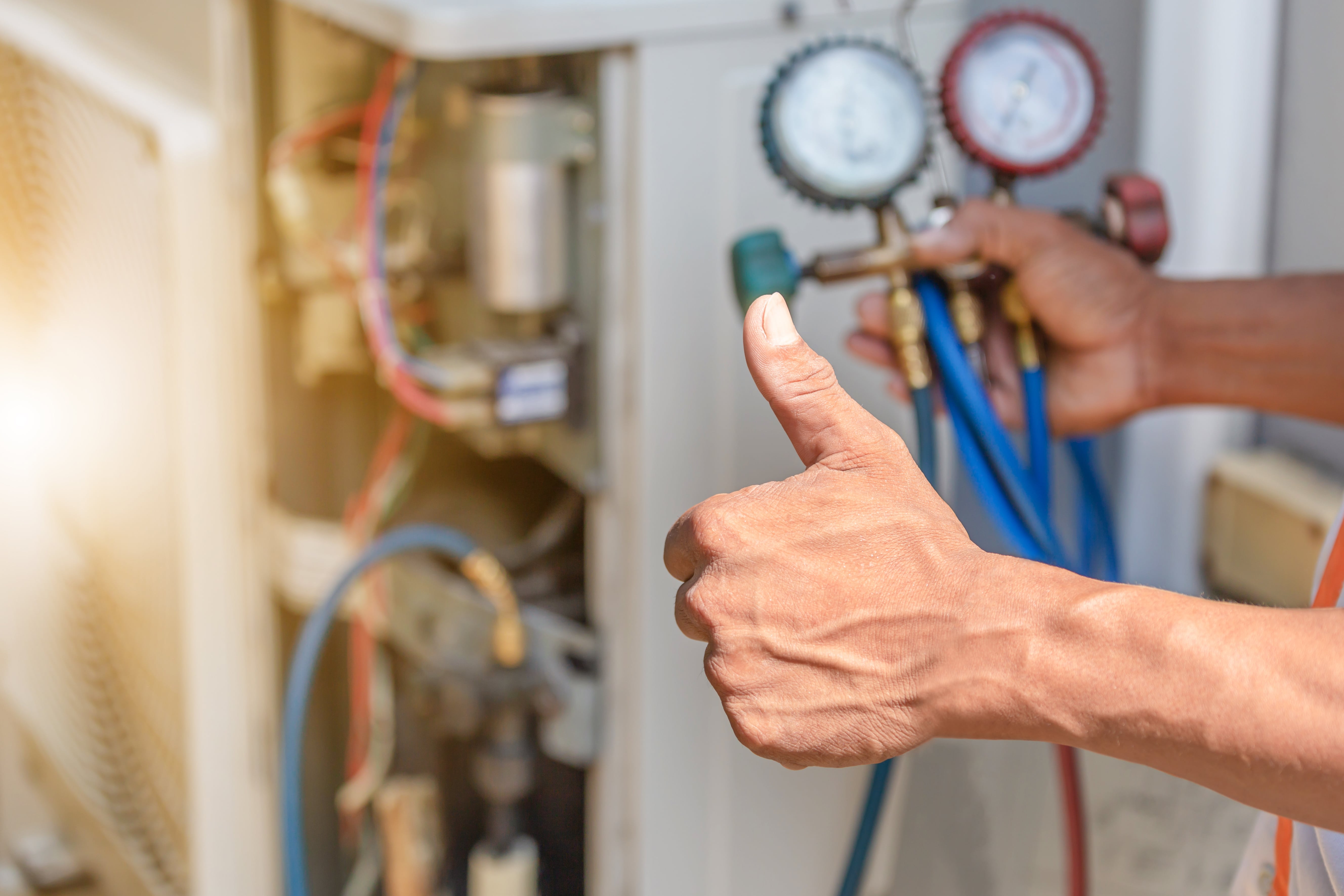 A maintenance worker giving a thumbs-up while checking HVAC equipment, highlighting the importance of property upkeep for tenant satisfaction.