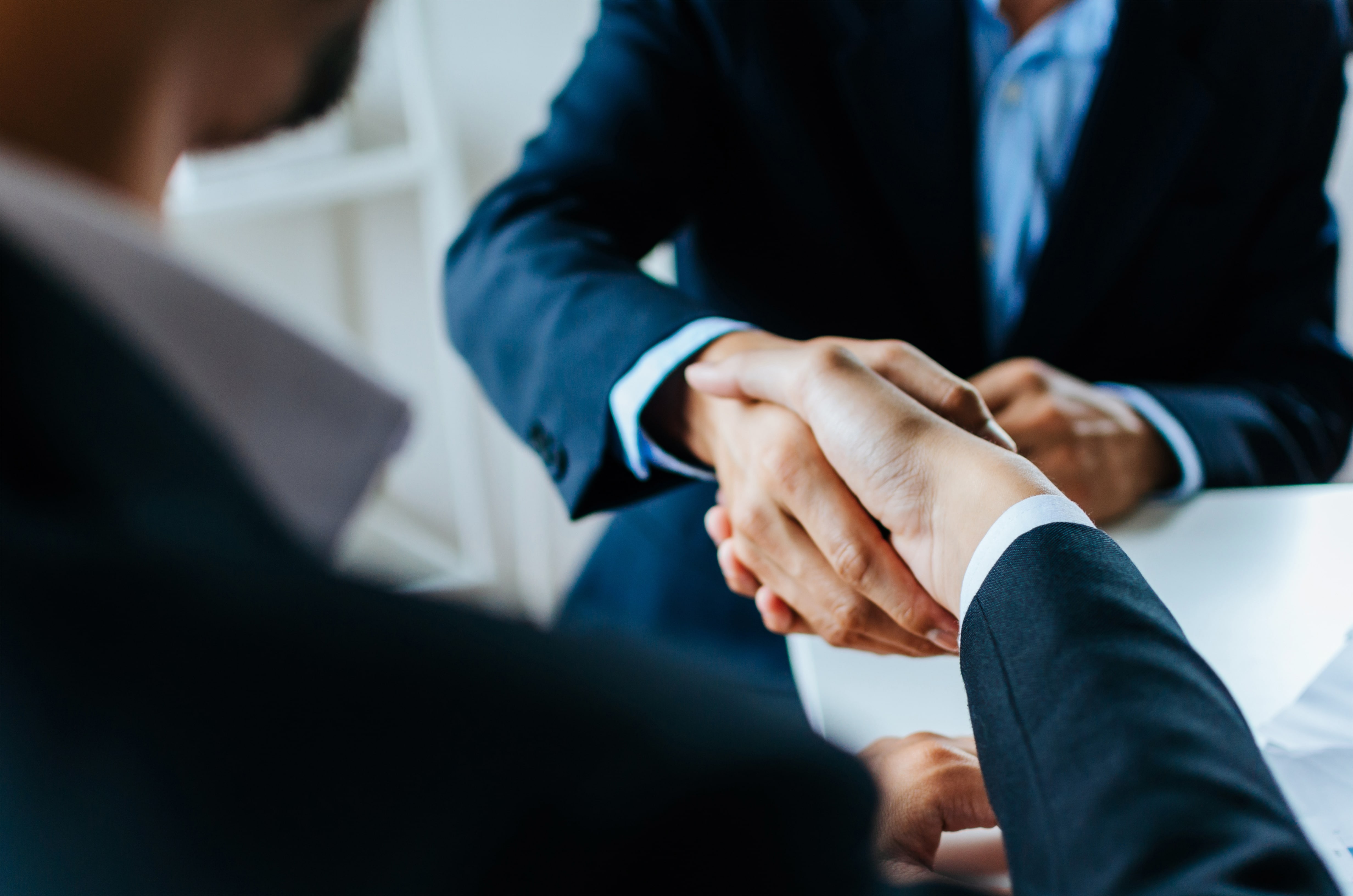 Two business professionals in suits shaking hands, symbolizing a property management agreement or landlord-tenant contract.