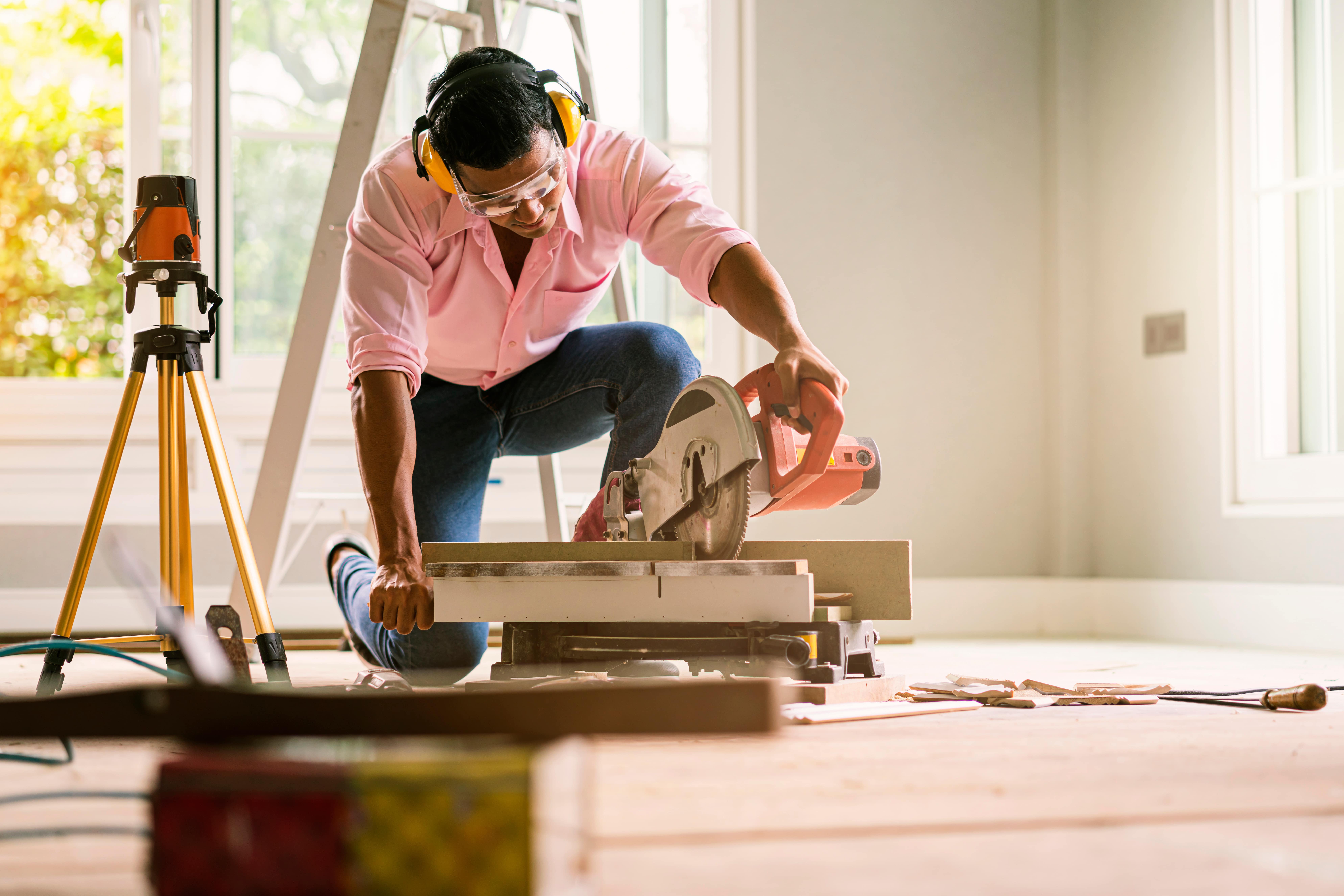 A construction worker using a circular saw on a wooden surface, representing property maintenance, home renovations, and real estate improvement projects.