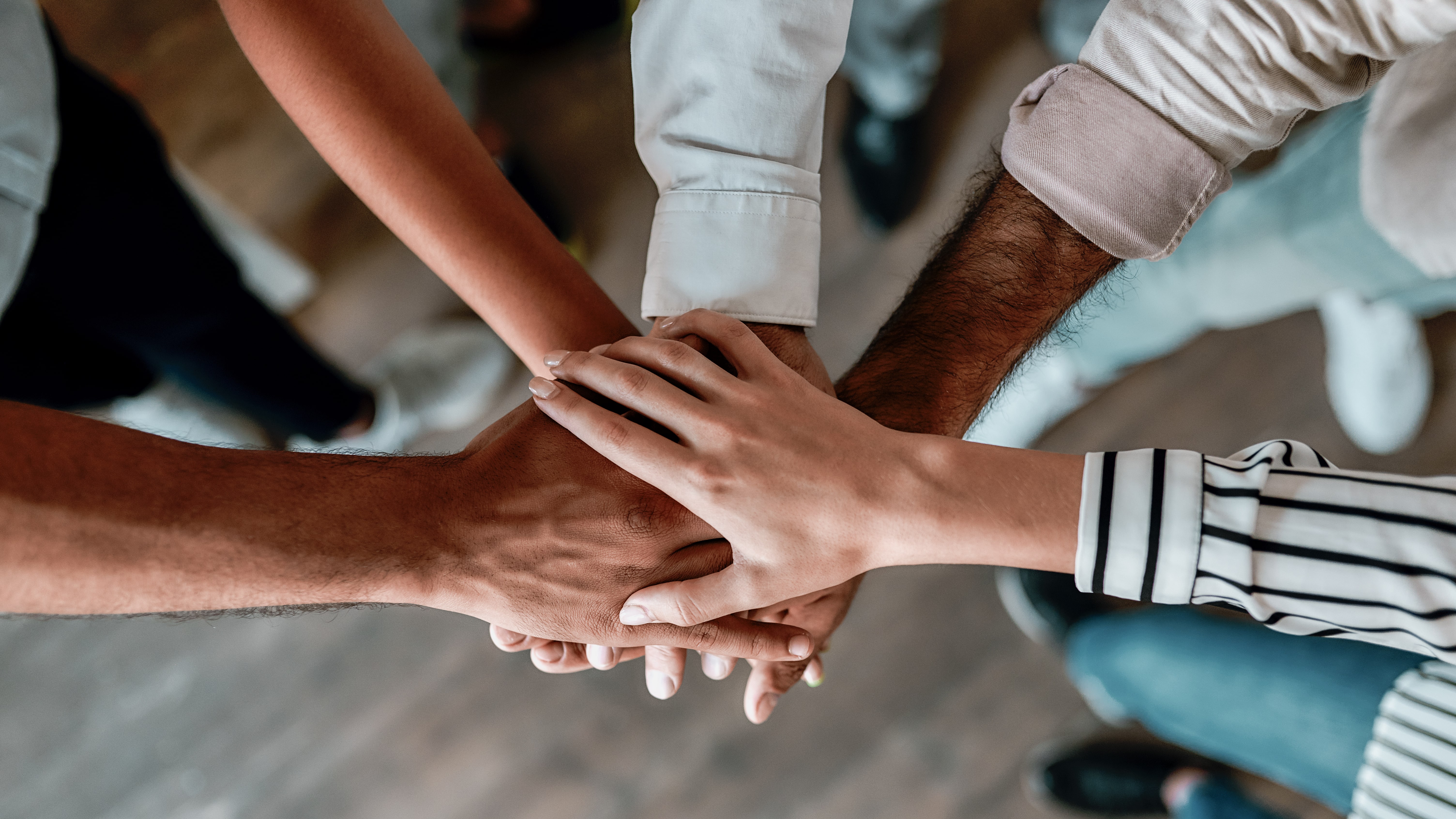 Diverse group of hands stacked together, symbolizing teamwork, inclusion, and fair housing practices.