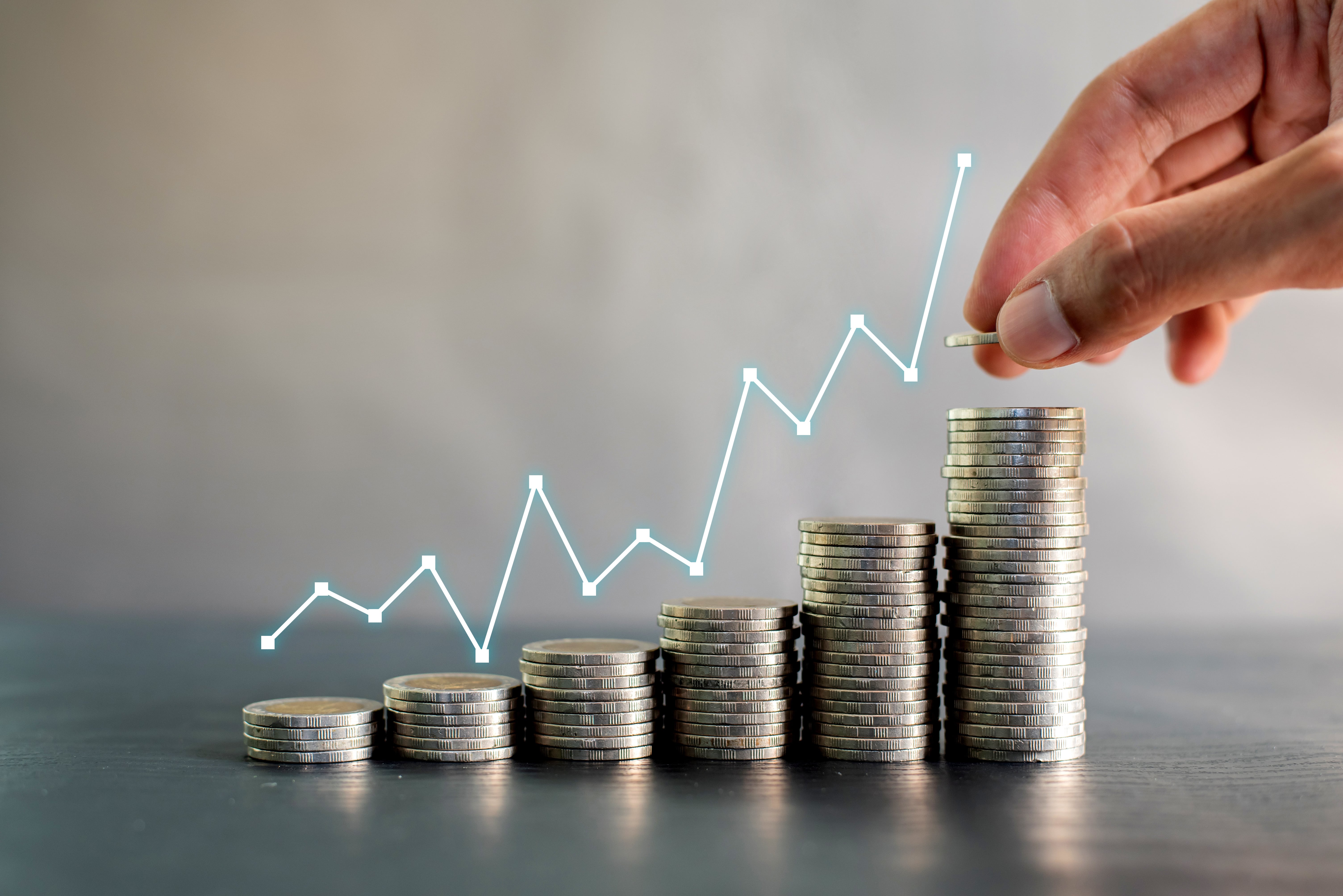 Stacks of silver coins with a rising financial graph, depicting investment growth and profitability in real estate.