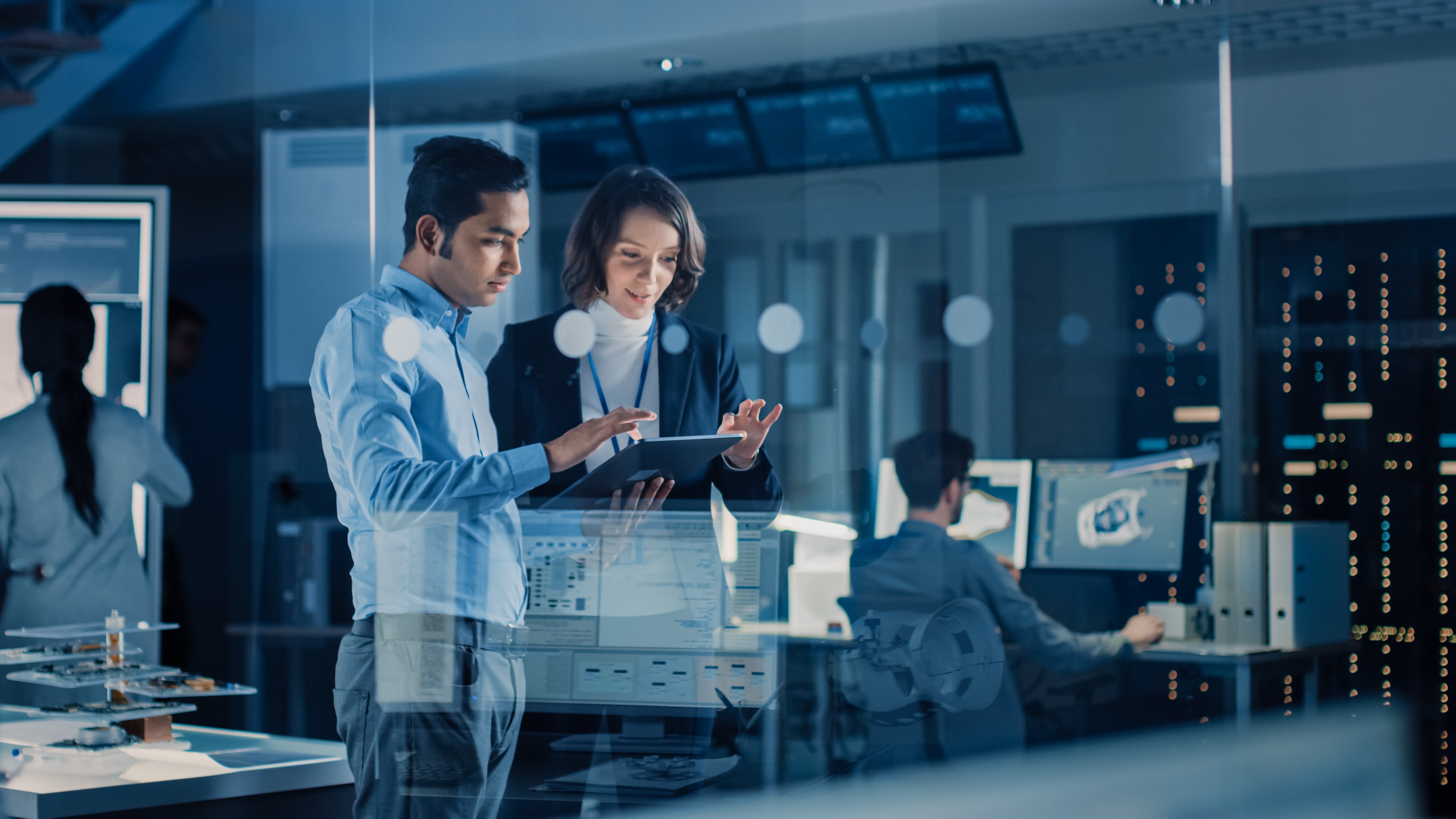 Two professionals analyzing data on a tablet in a high-tech office, representing digital property management solutions.