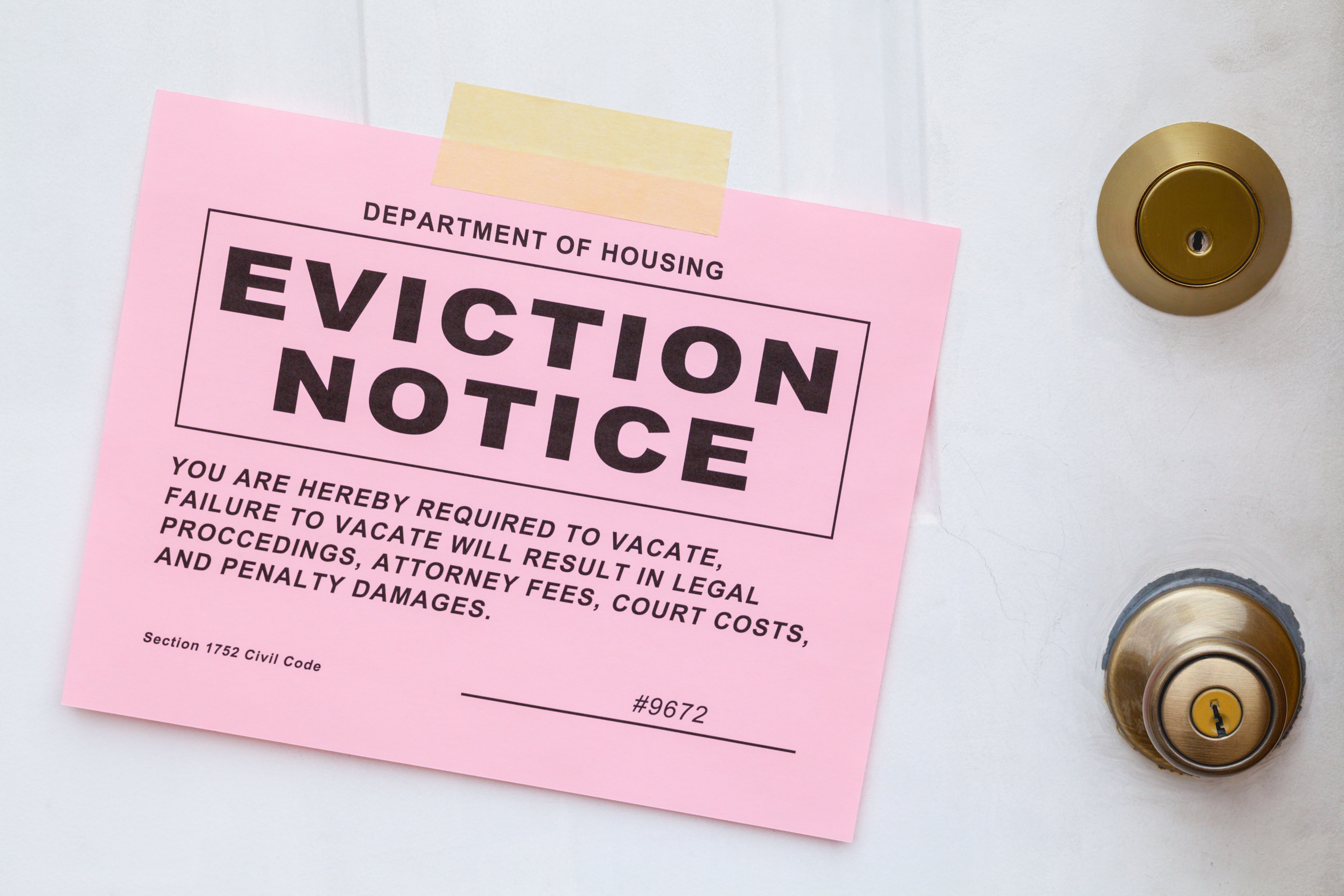 A pink eviction notice taped to a door, highlighting official housing notifications and consequences.