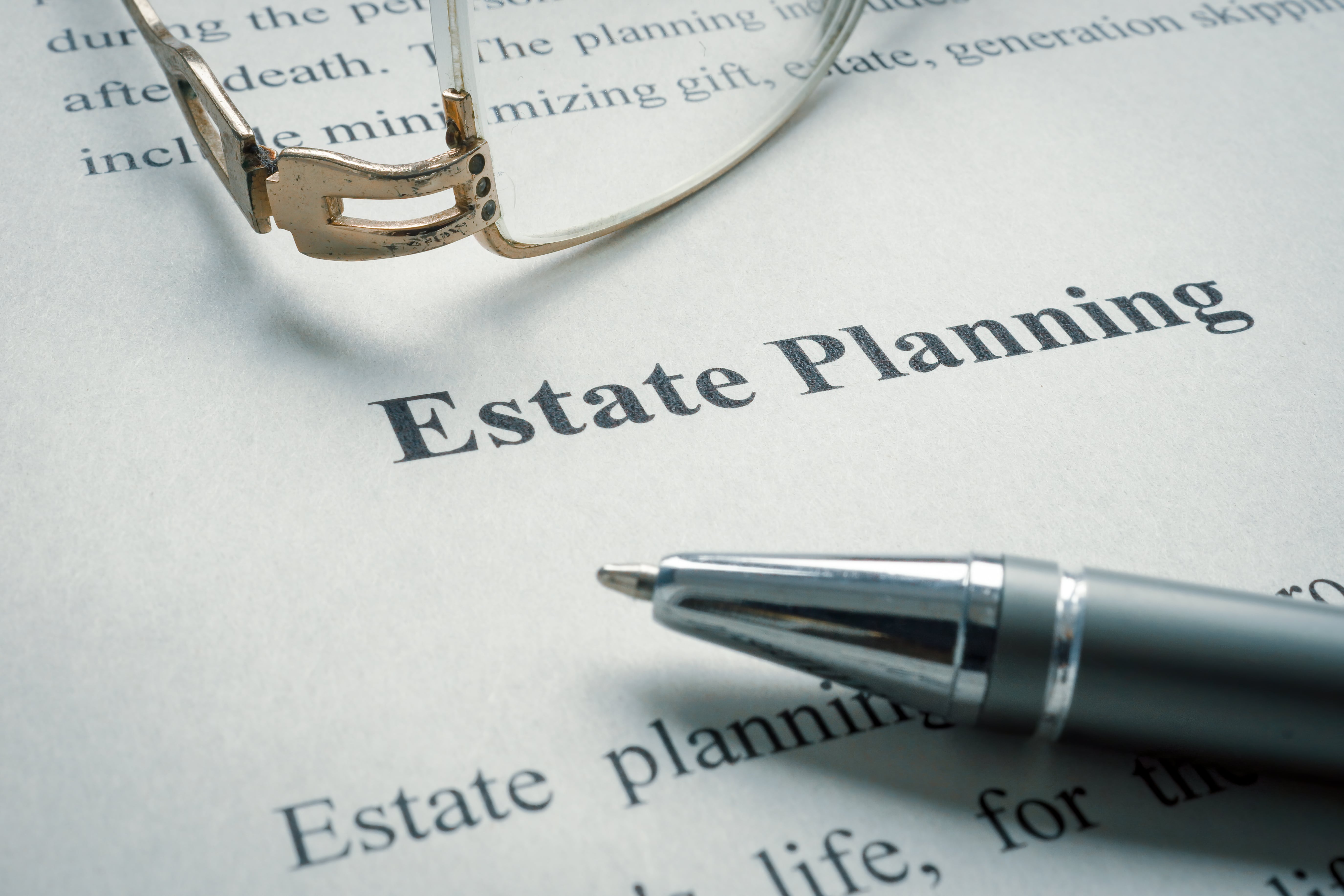 A close-up of an estate planning document with a pen and eyeglasses, emphasizing legal and financial preparation for asset management.