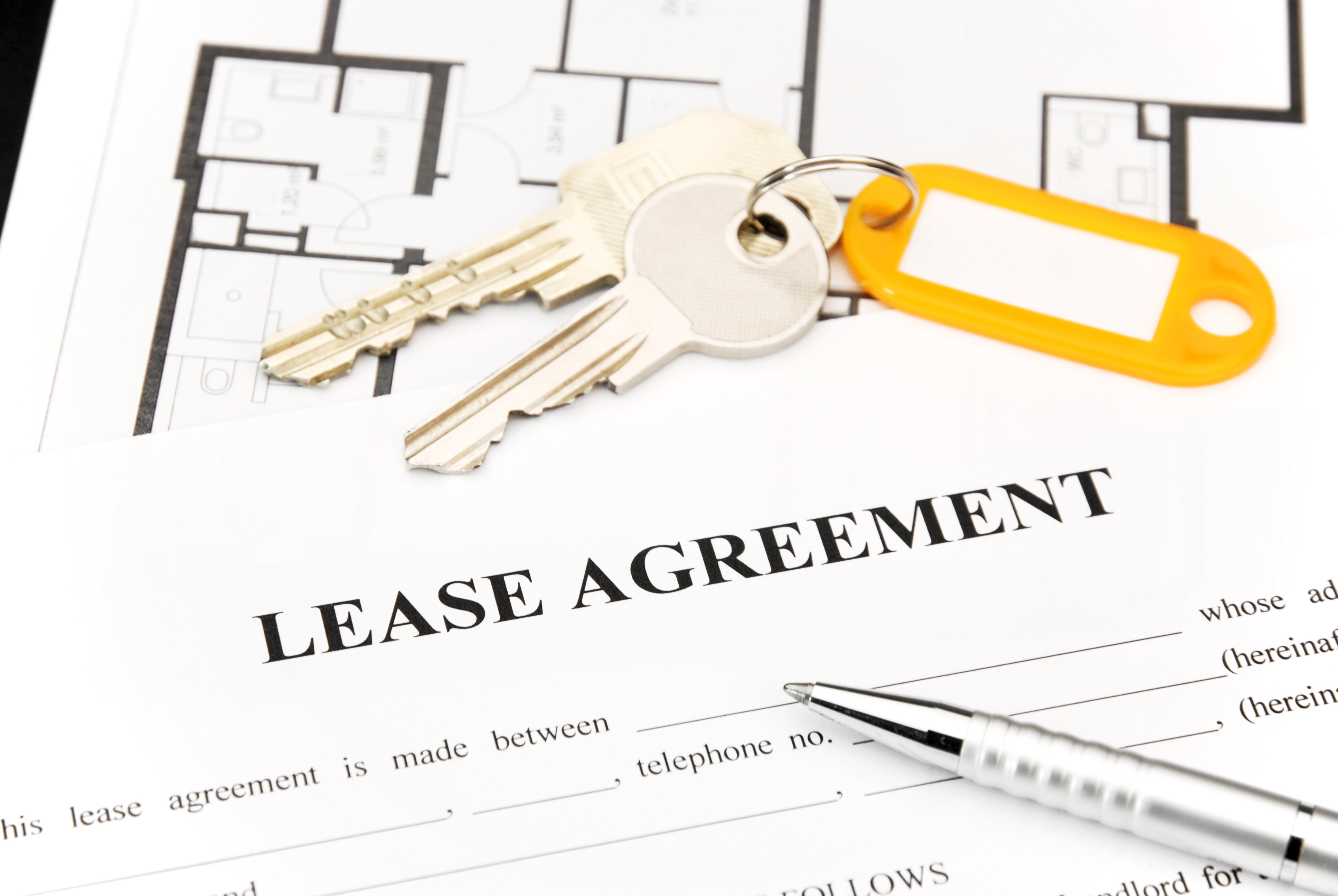 A lease agreement document with a set of keys and a pen placed on top, symbolizing rental or leasing processes.