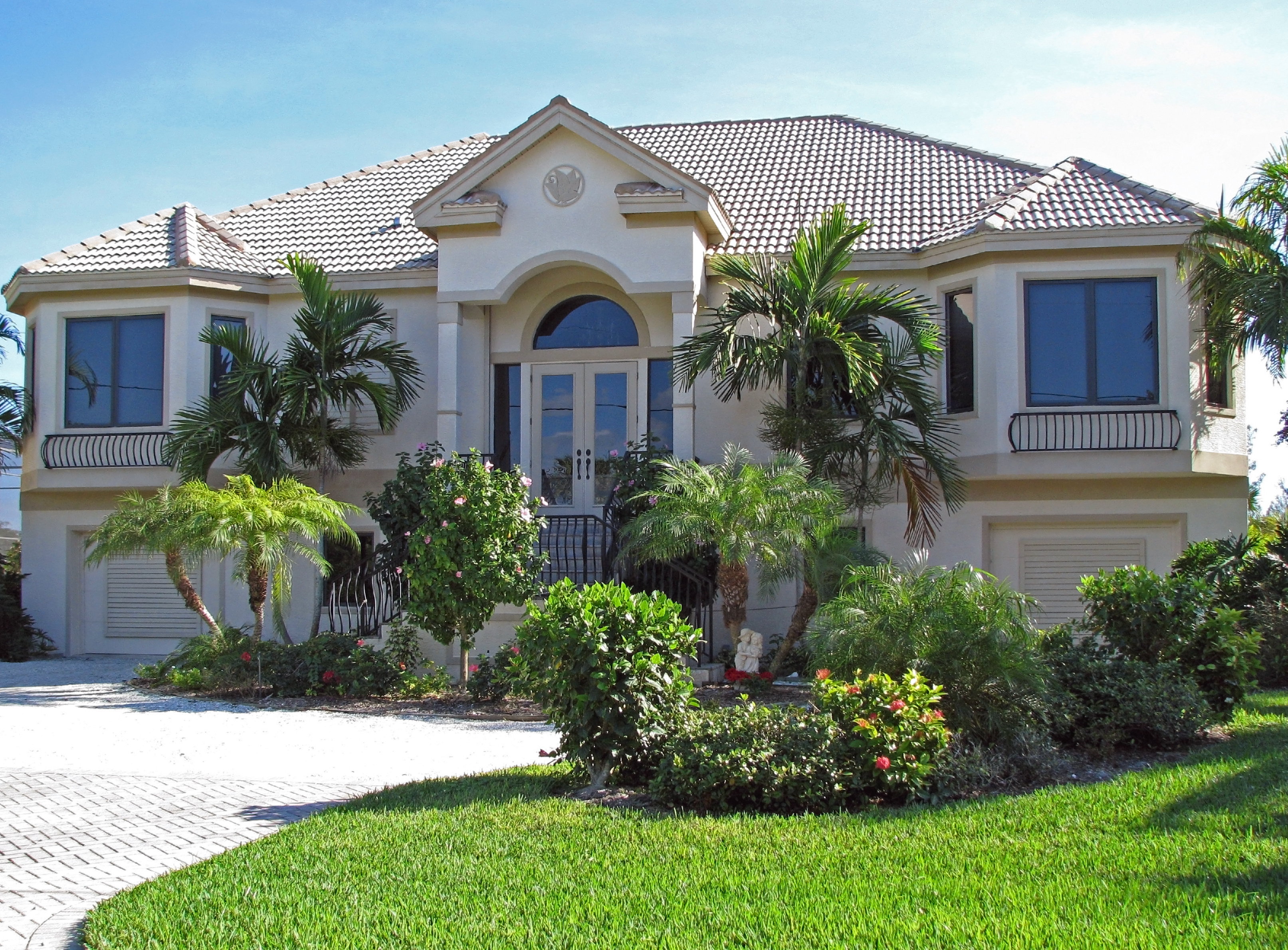 Beautiful two-story house with a tiled roof, lush landscaping, and large windows in a Kissimmee neighborhood with attractive housing