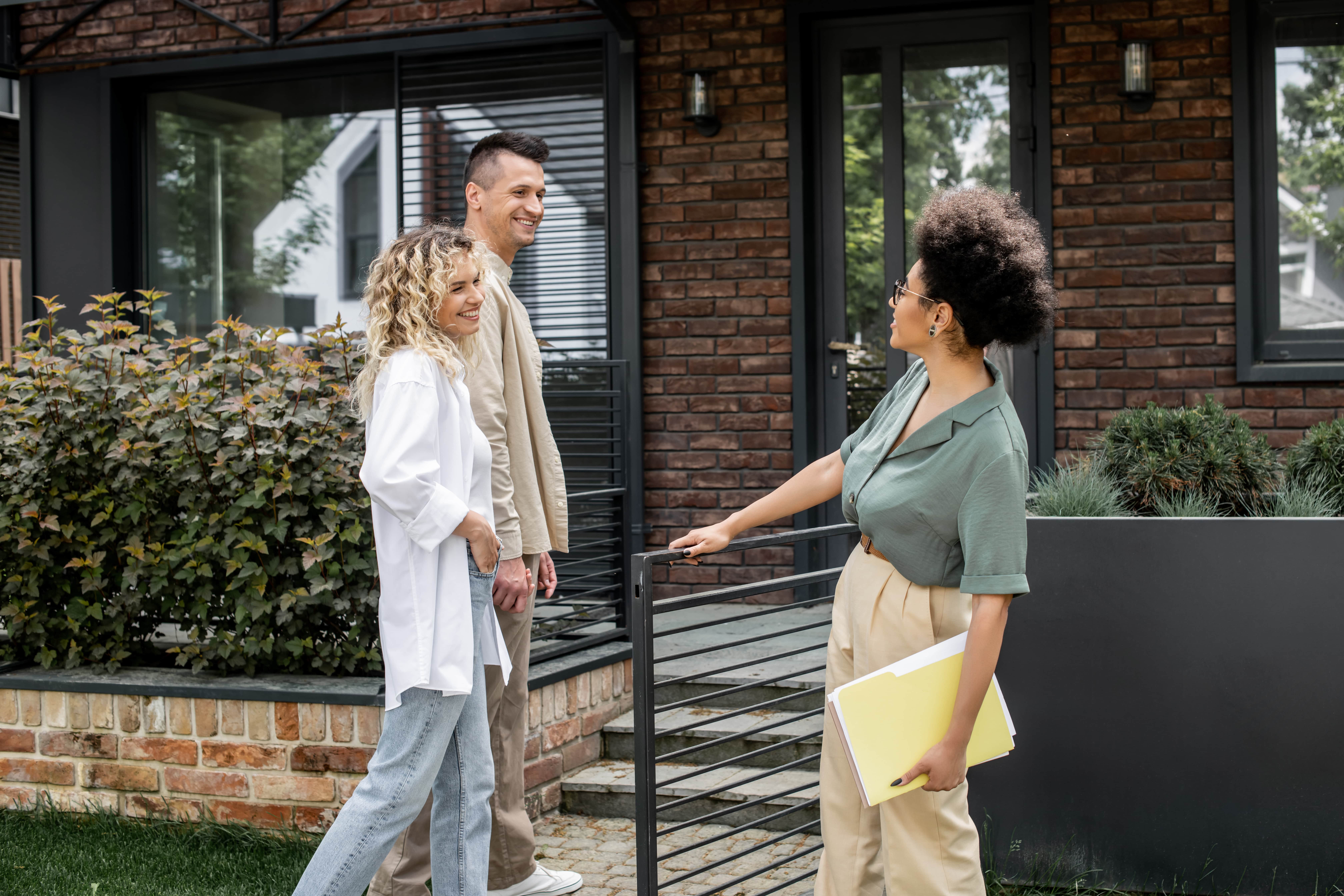 Property manager or real estate agent showing a smiling couple a modern home, symbolizing property sales, rentals, and customer service in the housing market.