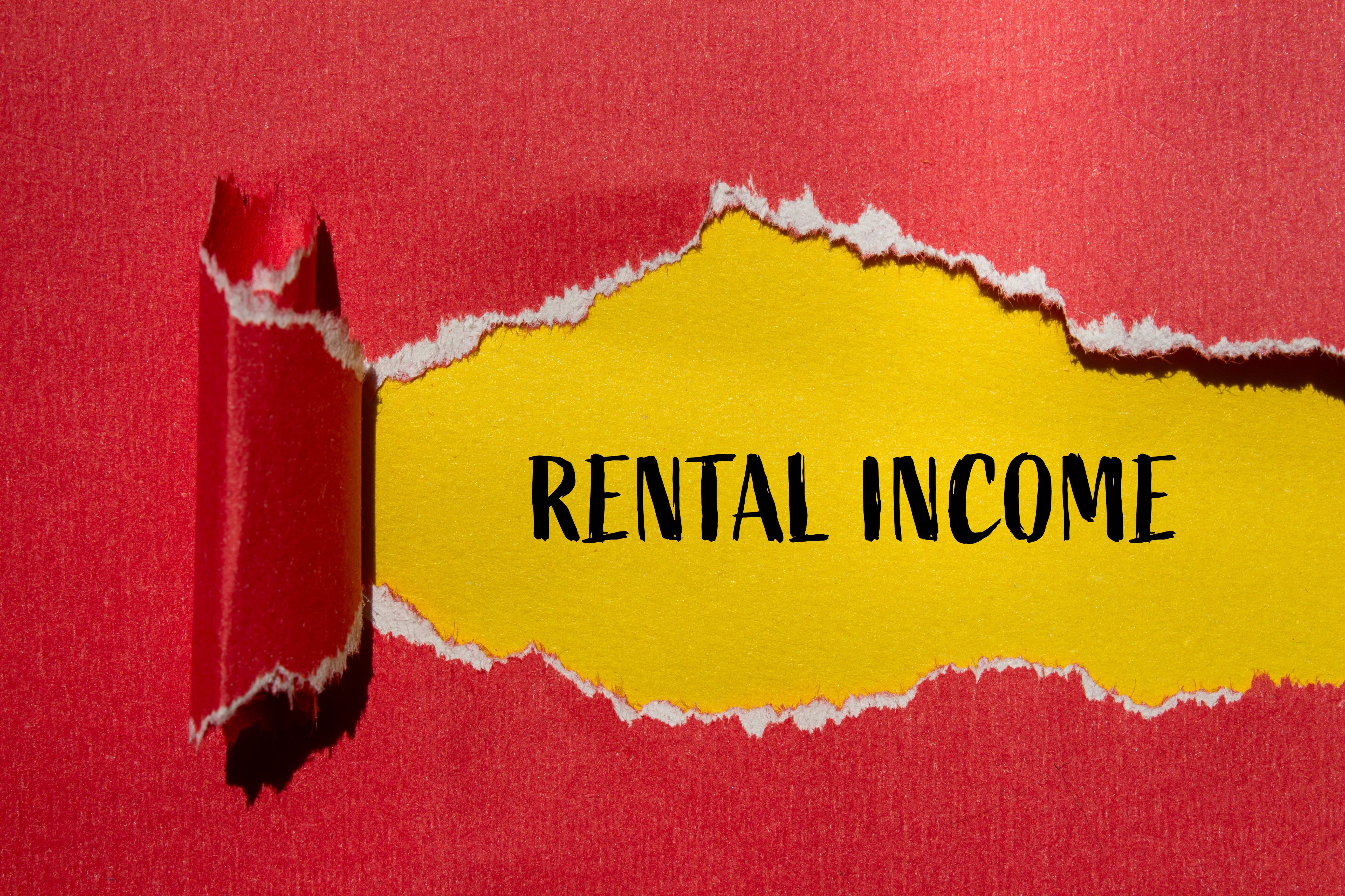 Torn red paper revealing the words 'Rental Income' on a yellow background, emphasizing real estate cash flow and investment returns.