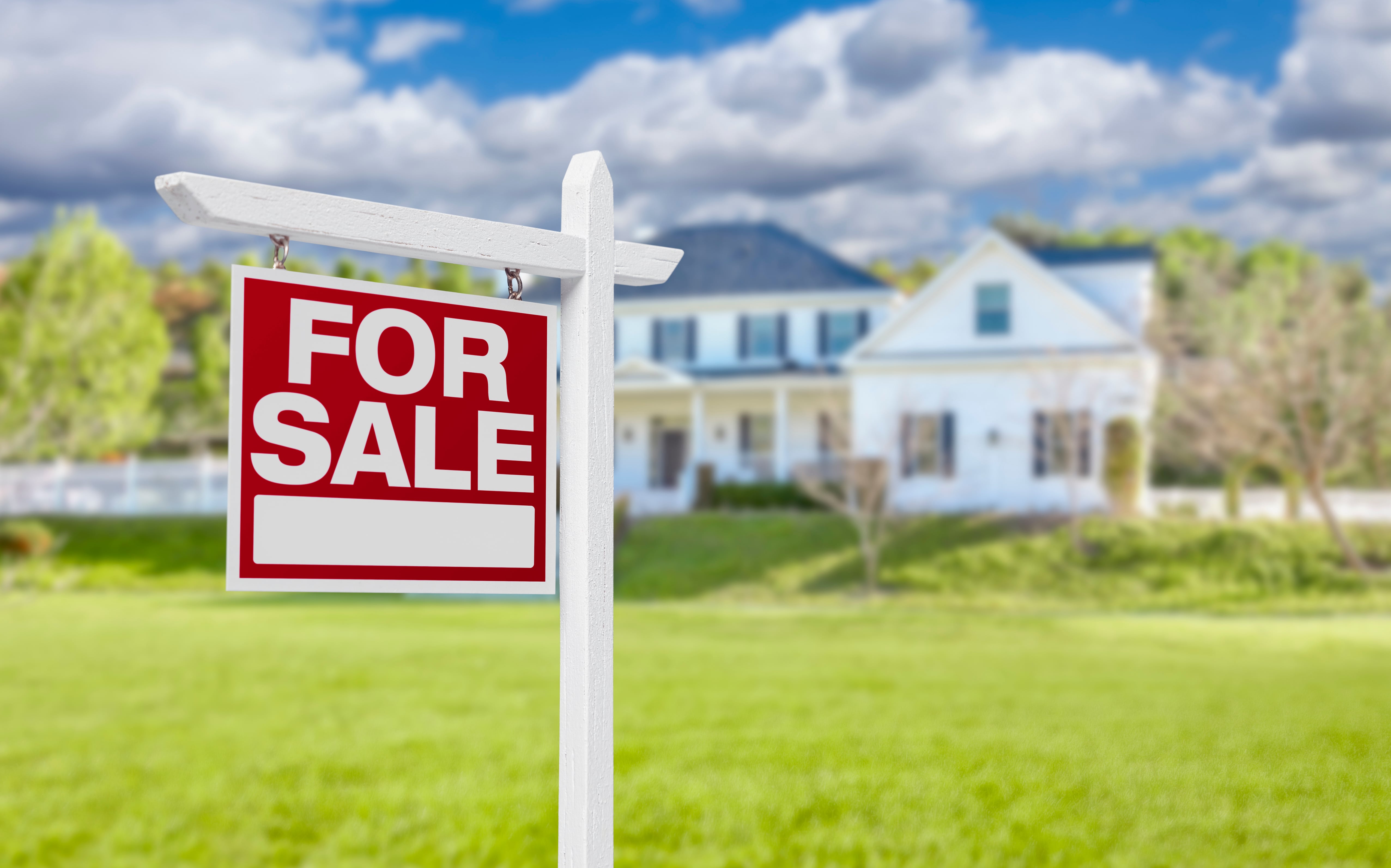 A ‘For Sale’ sign on a green lawn in front of a suburban home in Central Florida.