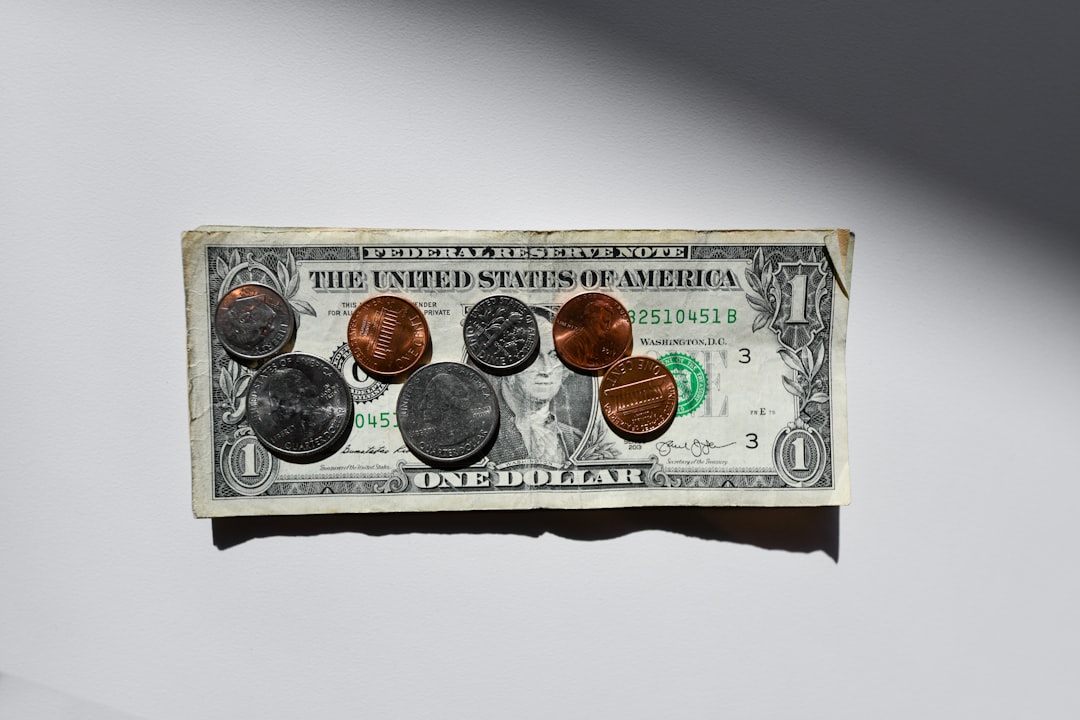 A dollar bill with various U.S. coins placed on it, creating a collage of currency. The image emphasizes the different denominations of money, highlighting financial themes.