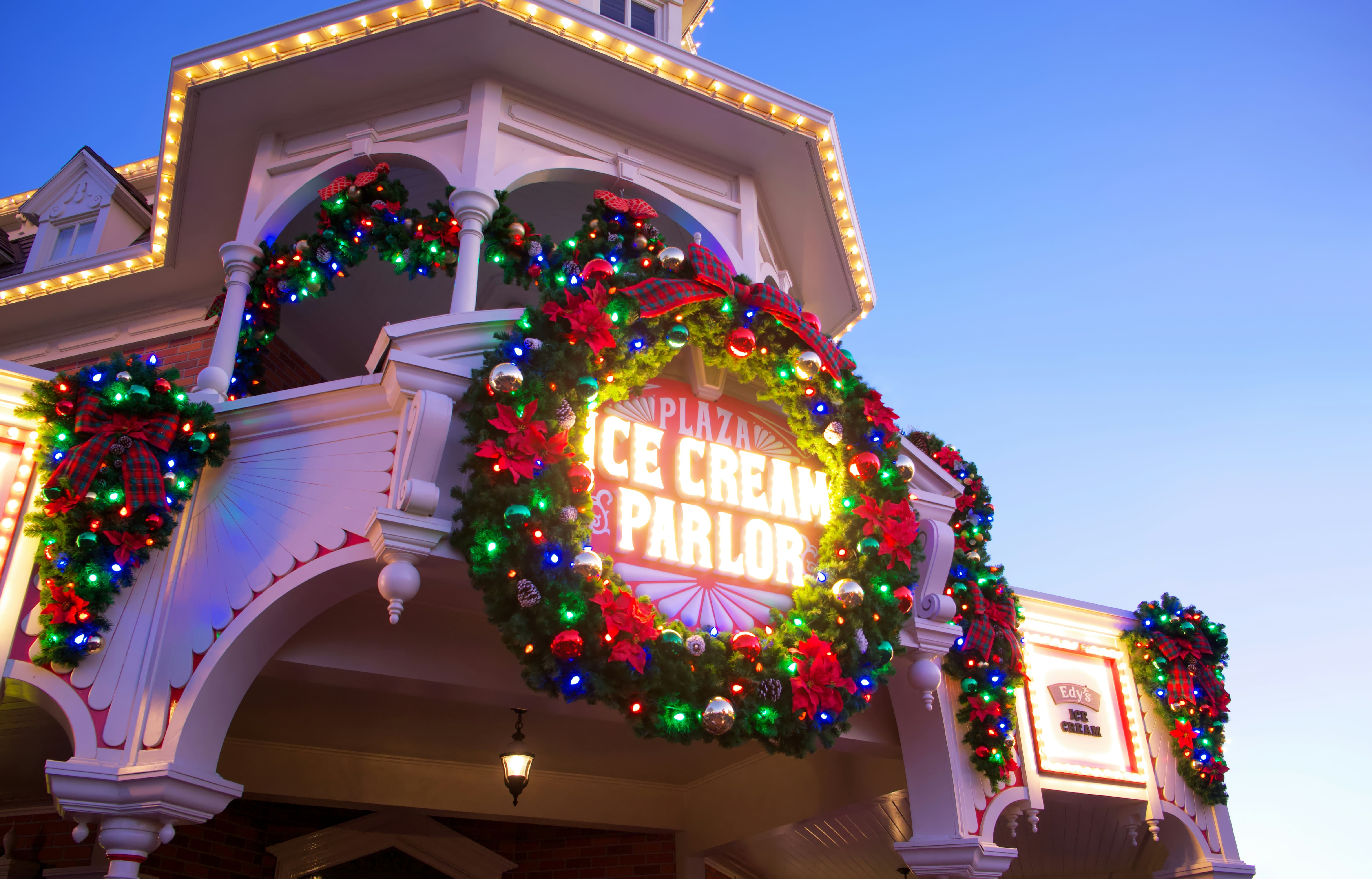 Disneys Plaza ice cream parlor adorned with holiday decorations, including wreaths, lights, and poinsettias, glowing warmly under a clear evening sky. Photo by Brian McGowan on Unsplash