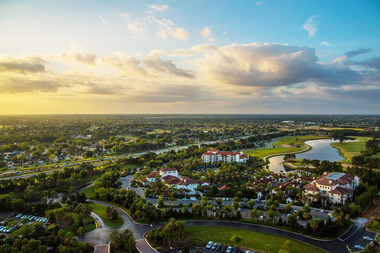 Aerial view of residential communities and golf course in Kissimmee, Florida at sunset, showcasing local property development and scenic landscape.