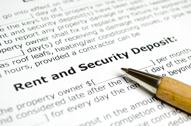Close-up of a rental agreement form highlighting the section titled Rent and Security Deposit with a pen resting on the document, symbolizing lease terms and tenant obligations.